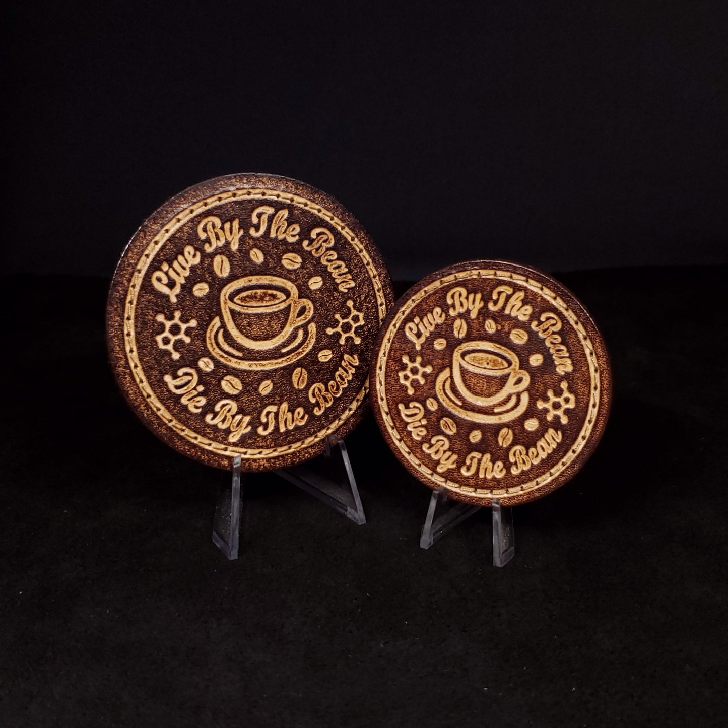Two brown circular velcro patches embossed with text and graphics of a mug, coffee beans, and caffeine molecules. 