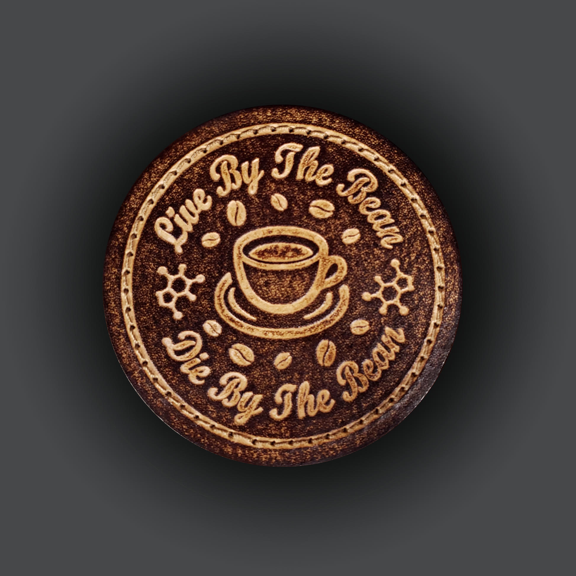 Brown circular velcro patch embossed with coffee themed graphics and text that says "Live by the bean, die by the bean"