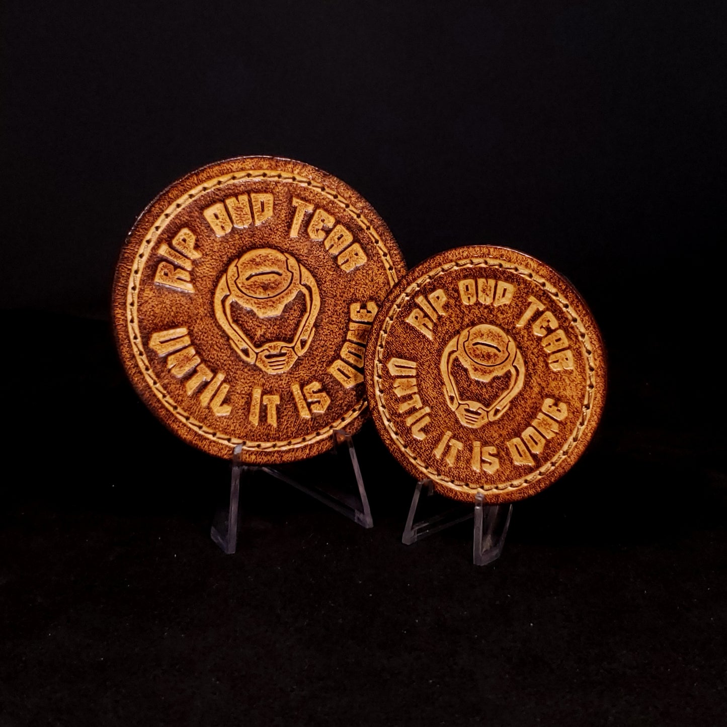Two brown leather velcro patches embossed with text and the Doom slayer's helmet, posed on a black background.