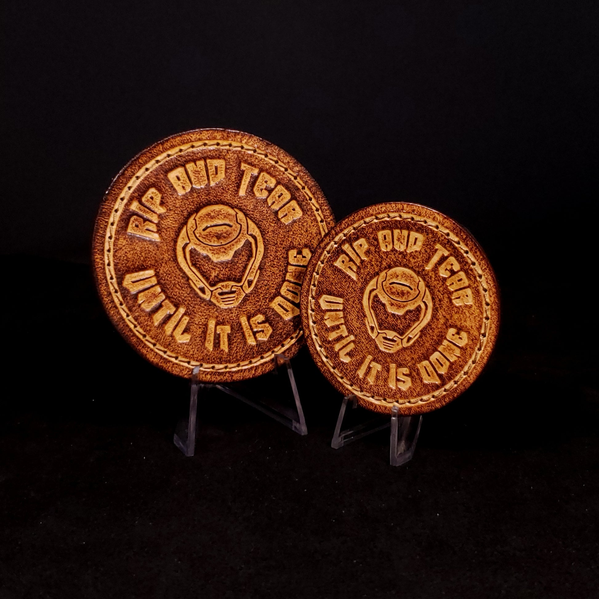 Two brown leather velcro patches embossed with text and the Doom slayer's helmet, posed on a black background.