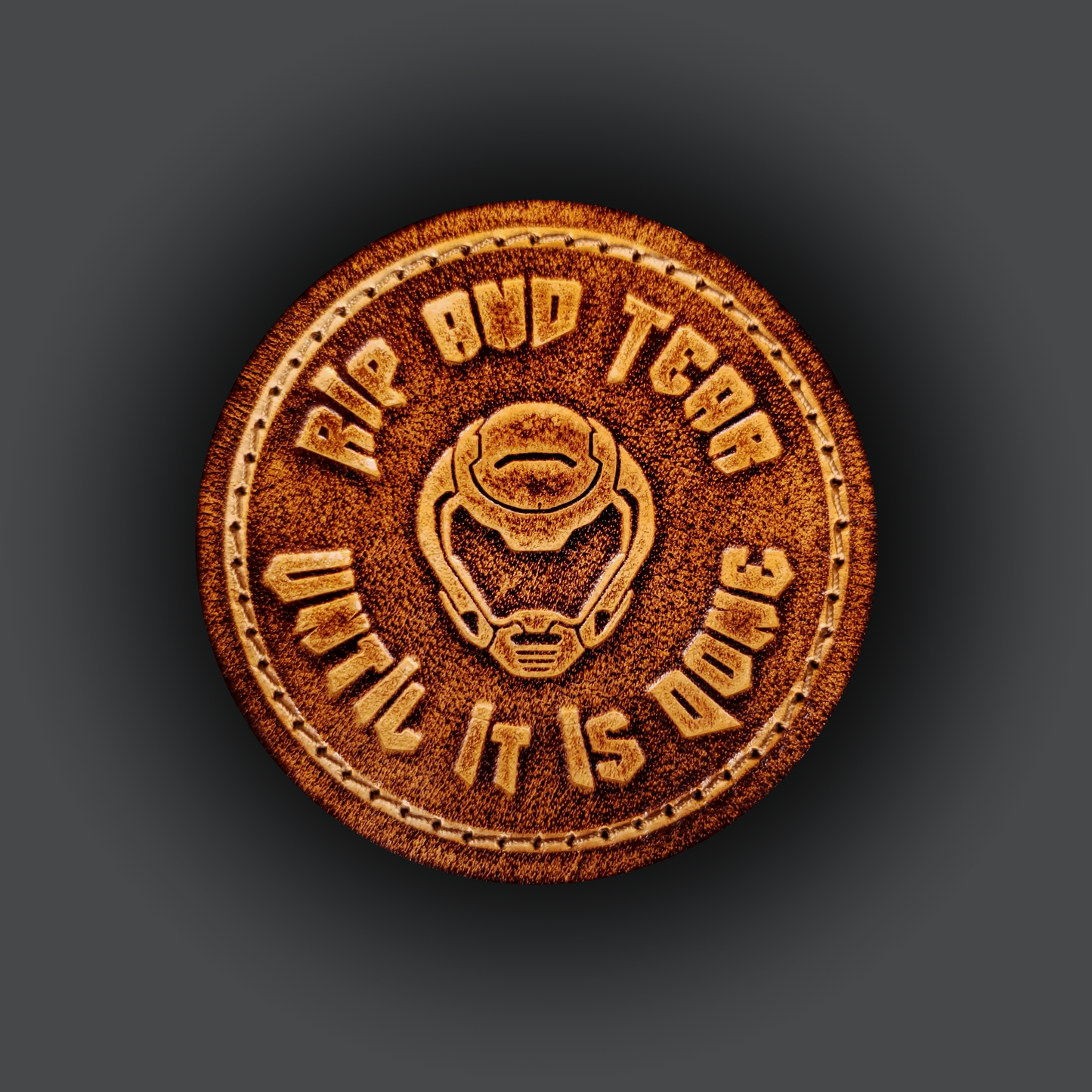 Brown leather velcro patch embossed with text that says "Rip and tear until it is done" and a helmet from the Doom franchise.