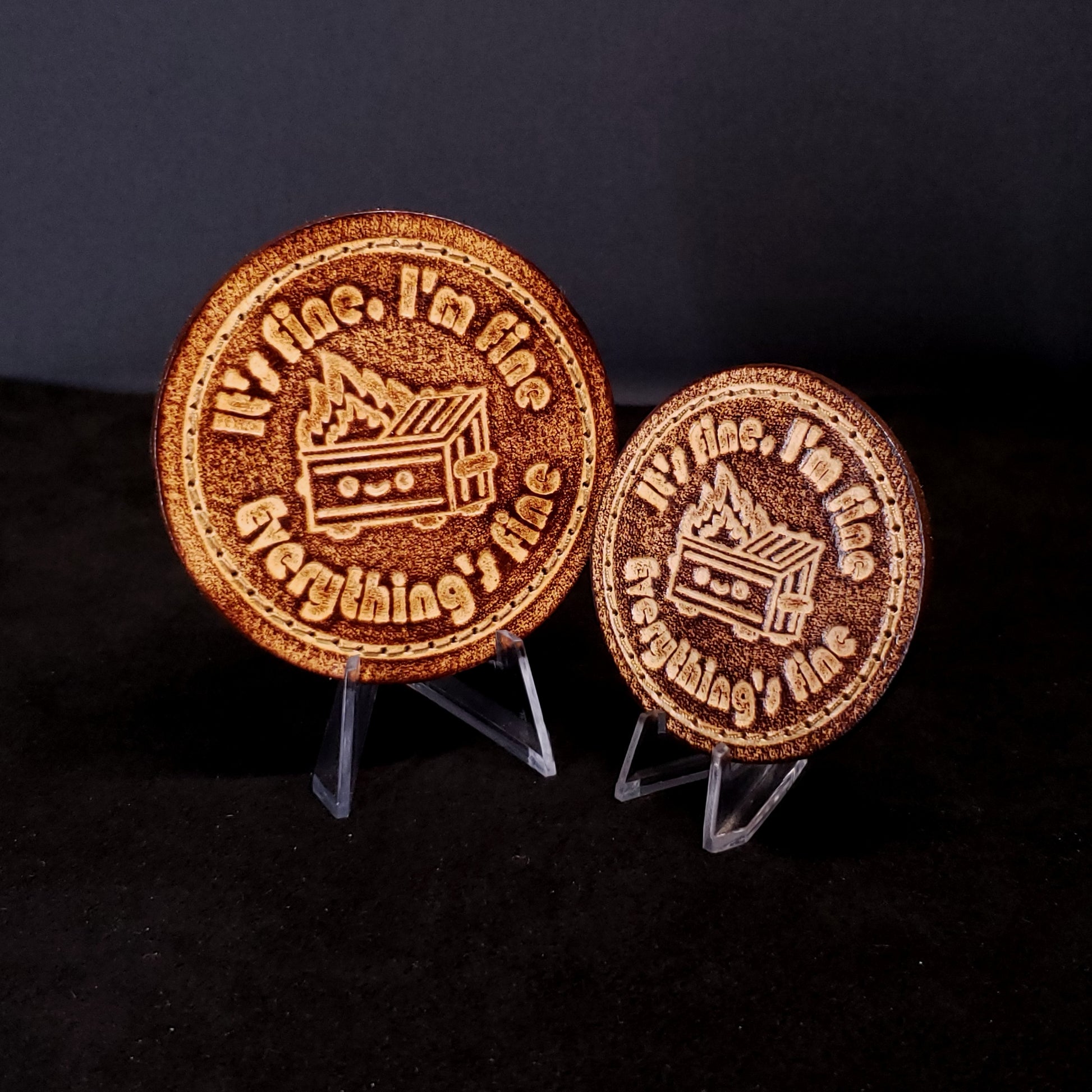 Two brown leather velcro patches featuring funny text and a cartoon graphic of a dumpster fire, posed on a black background.