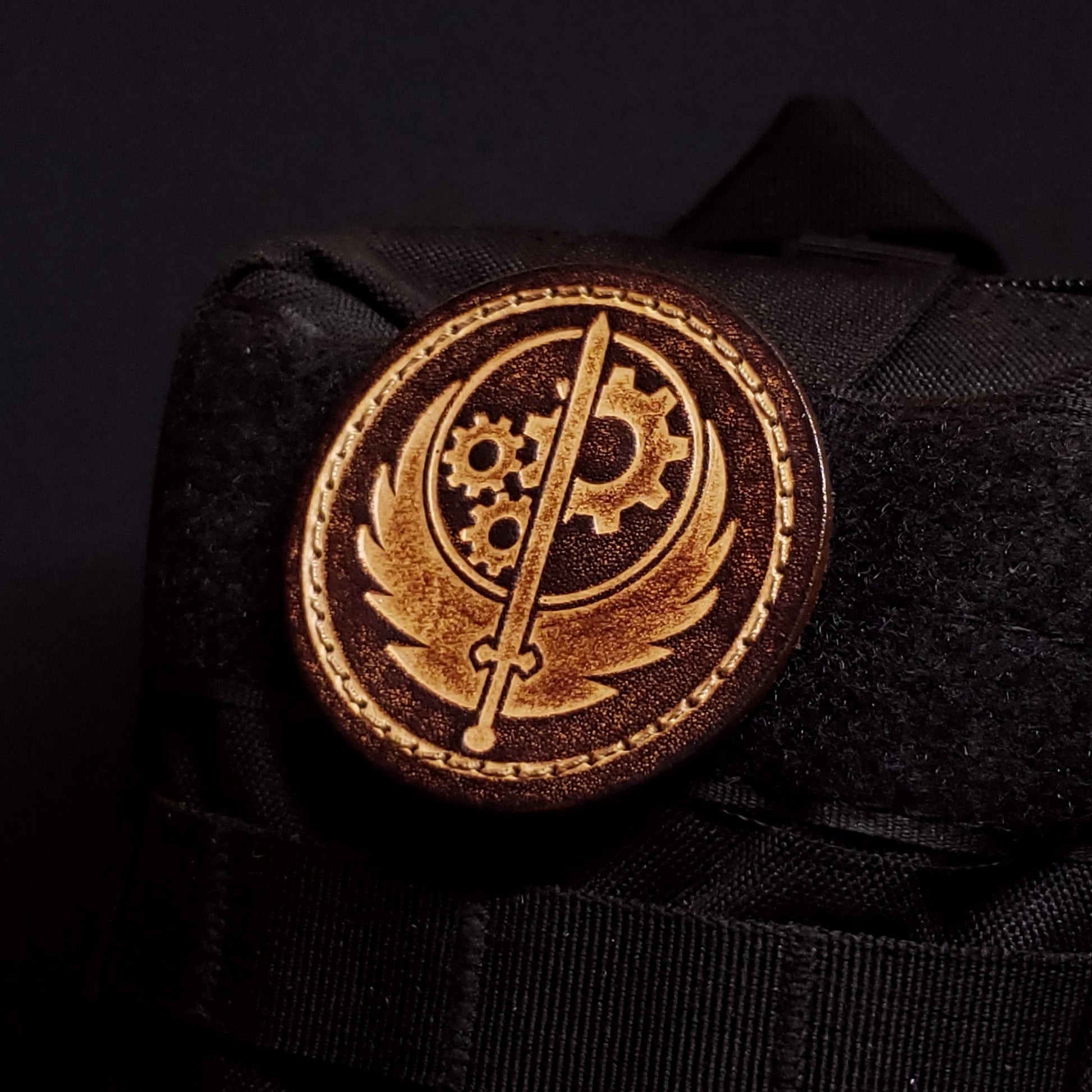 Brown circular velcro patch embossed with the Brotherhood of Steel emblem, affixed to a bag.