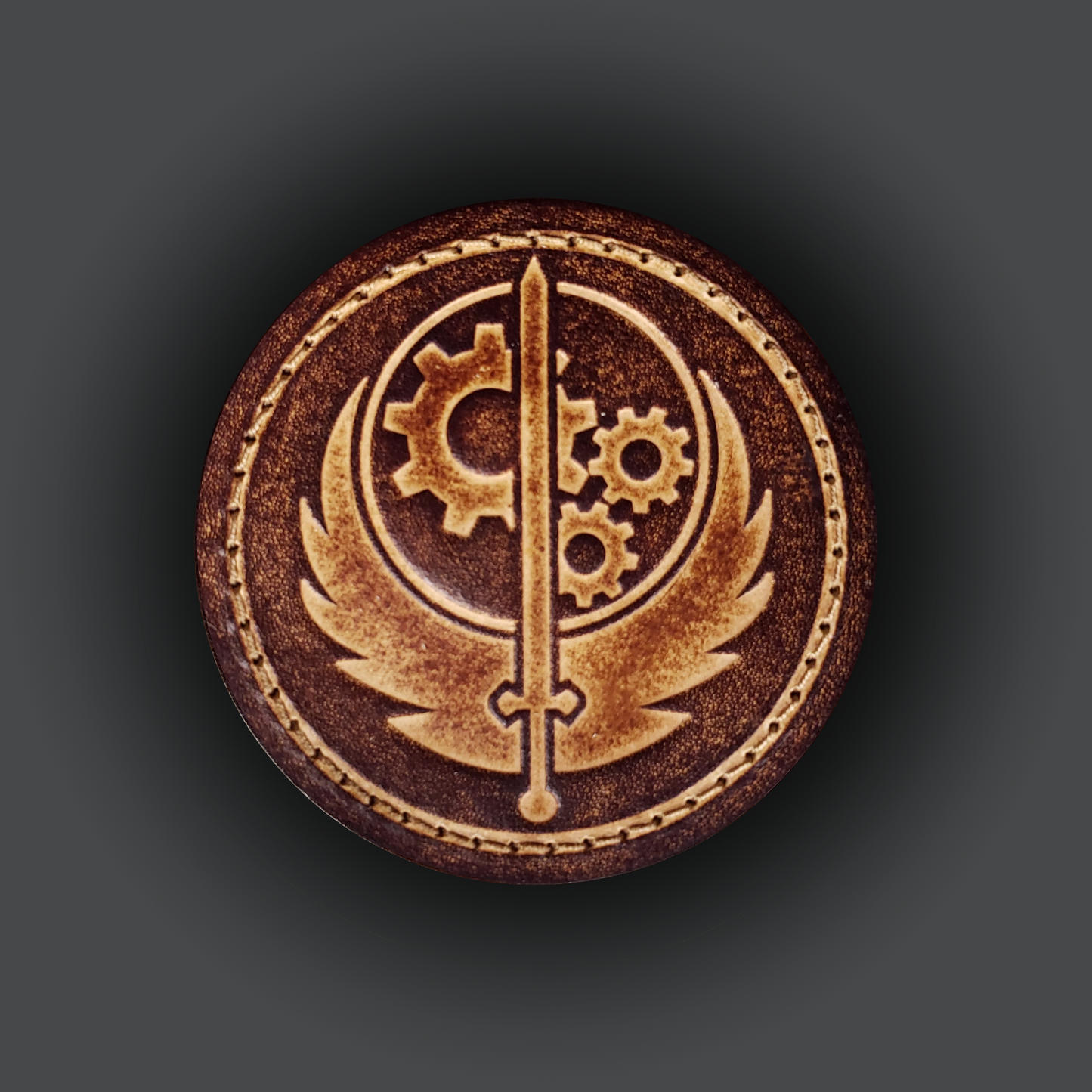 Brown circular velcro patch embossed with the Brotherhood of Steel emblem from the Fallout franchise.