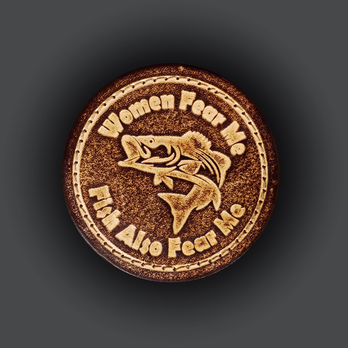 Brown circular velcro patch embossed with a graphic of a fish and text that says "Women fear me, fish fear me".