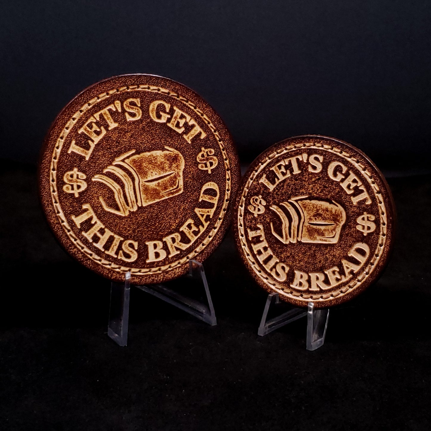 Two brown leather velcro patches embossed with text and graphics of slice bread and dollar signs.