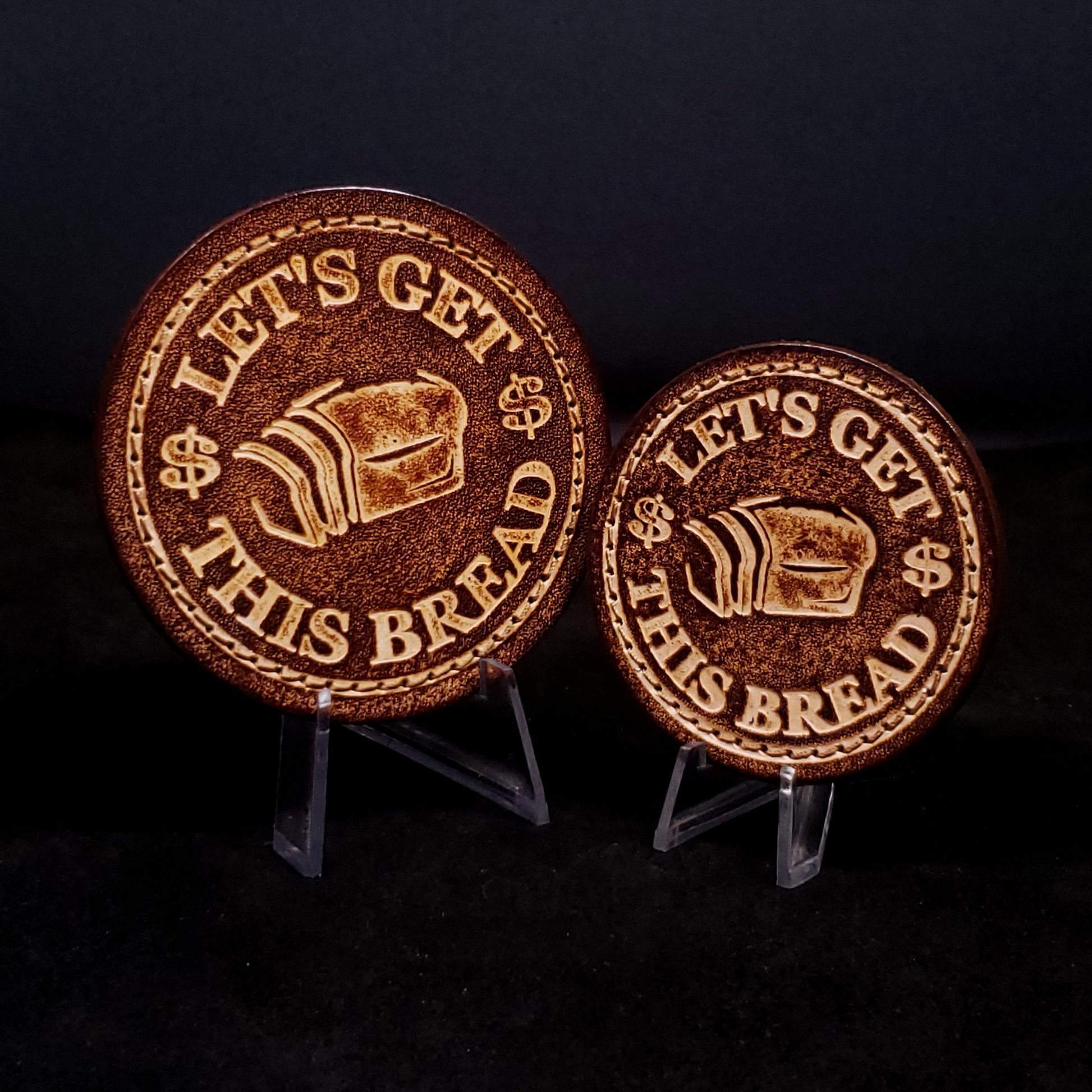 Two brown leather velcro patches embossed with text and graphics of slice bread and dollar signs.