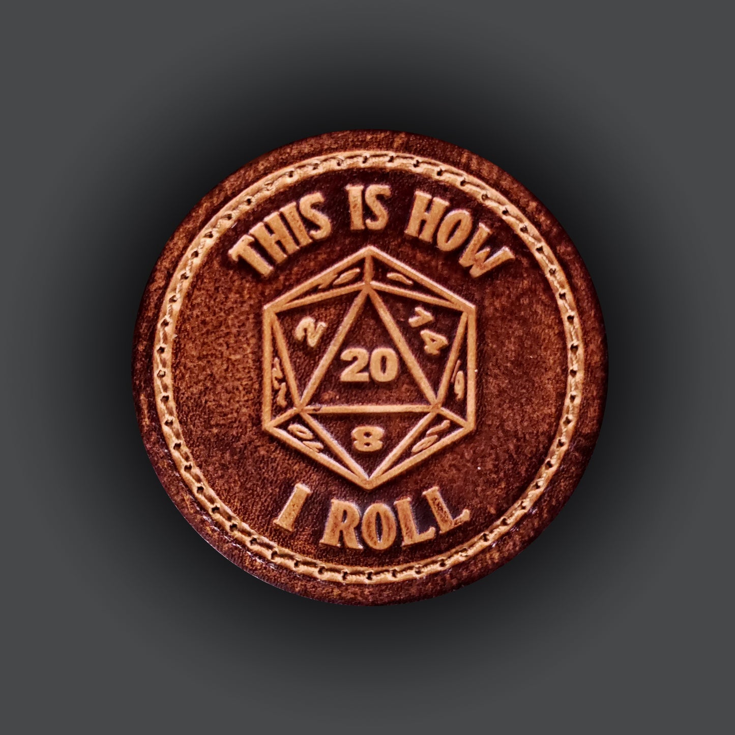 Brown leather velcro patch with text that says "This is how I roll" and an image of a twenty sided die with the number twenty facing up.