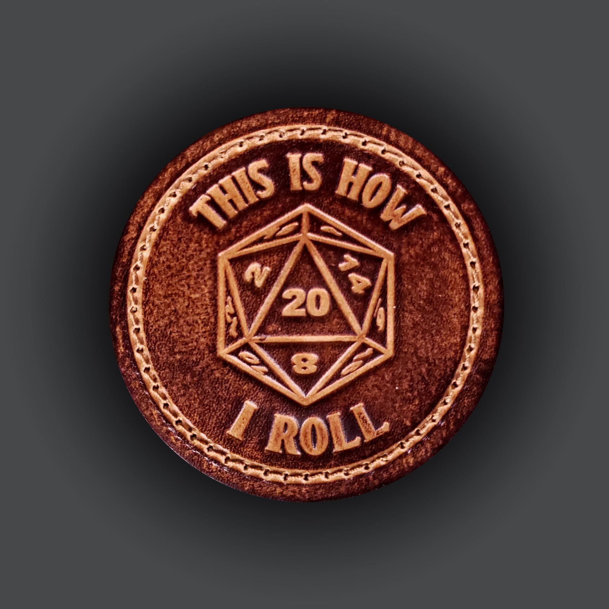 Brown leather velcro patch with text that says "This is how I roll" and an image of a twenty sided die with the number twenty facing up.
