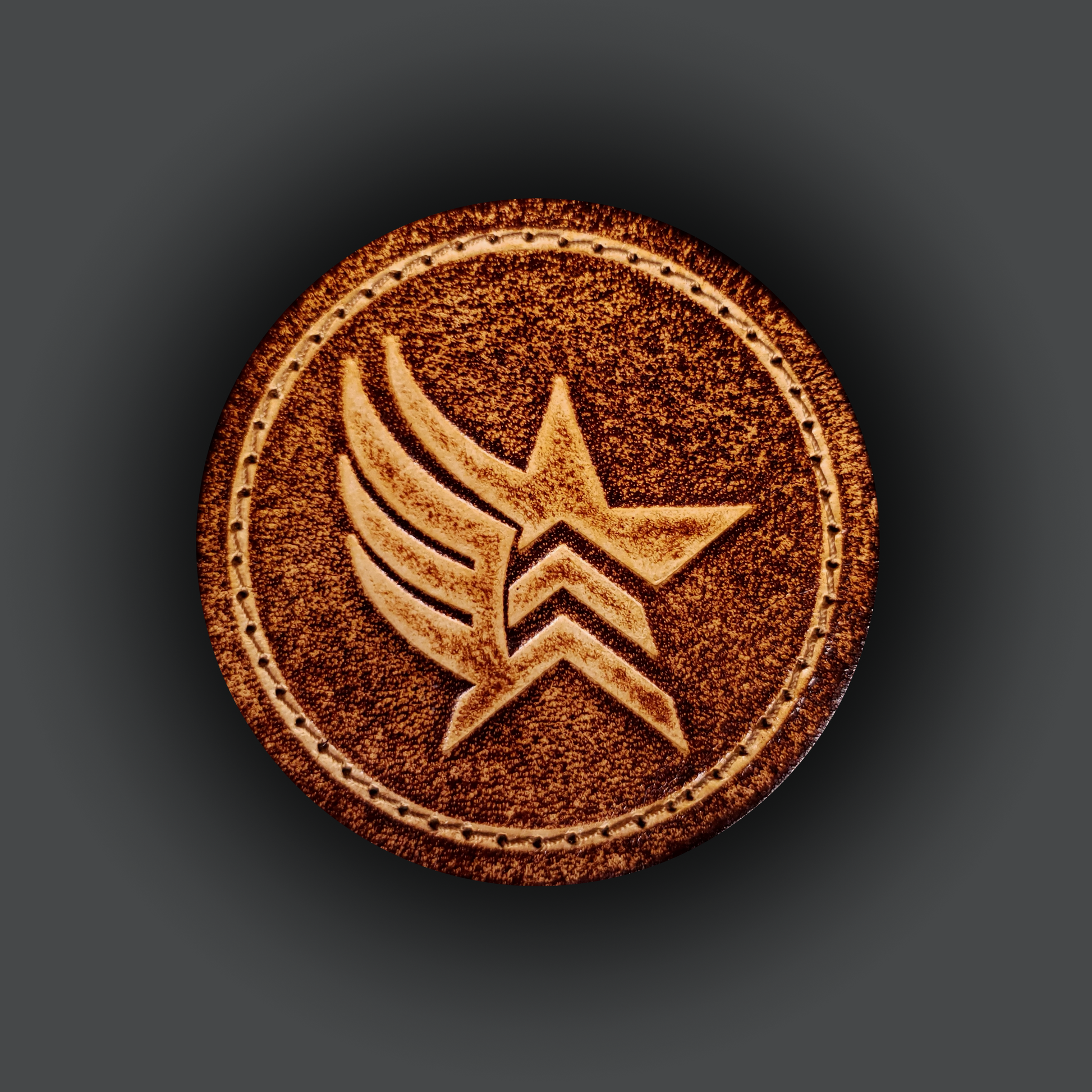 Brown leather velcro patch embossed with a star and wing symbol from the Mass Effect franchise.