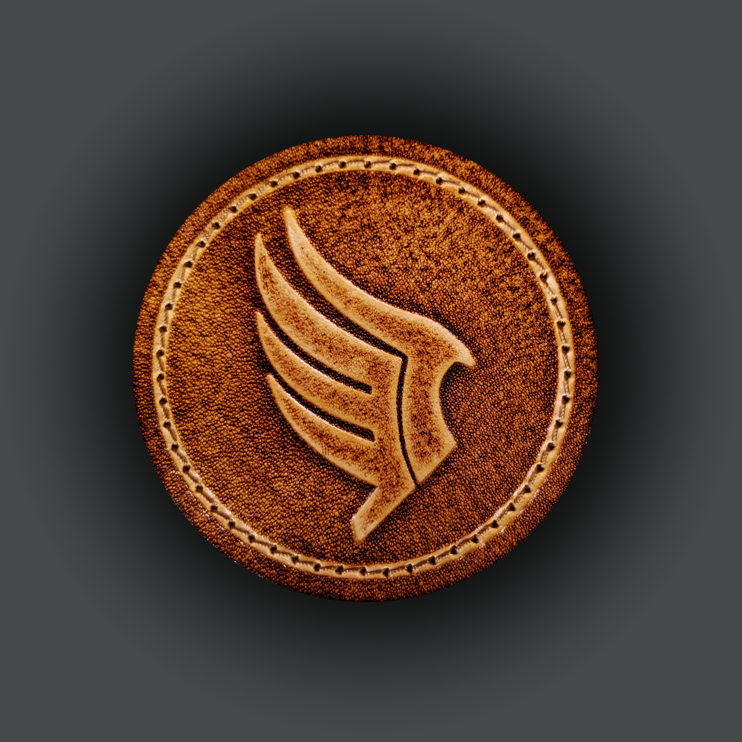 Brown leather velcro patch embossed with a wing symbol from the Mass Effect franchise.