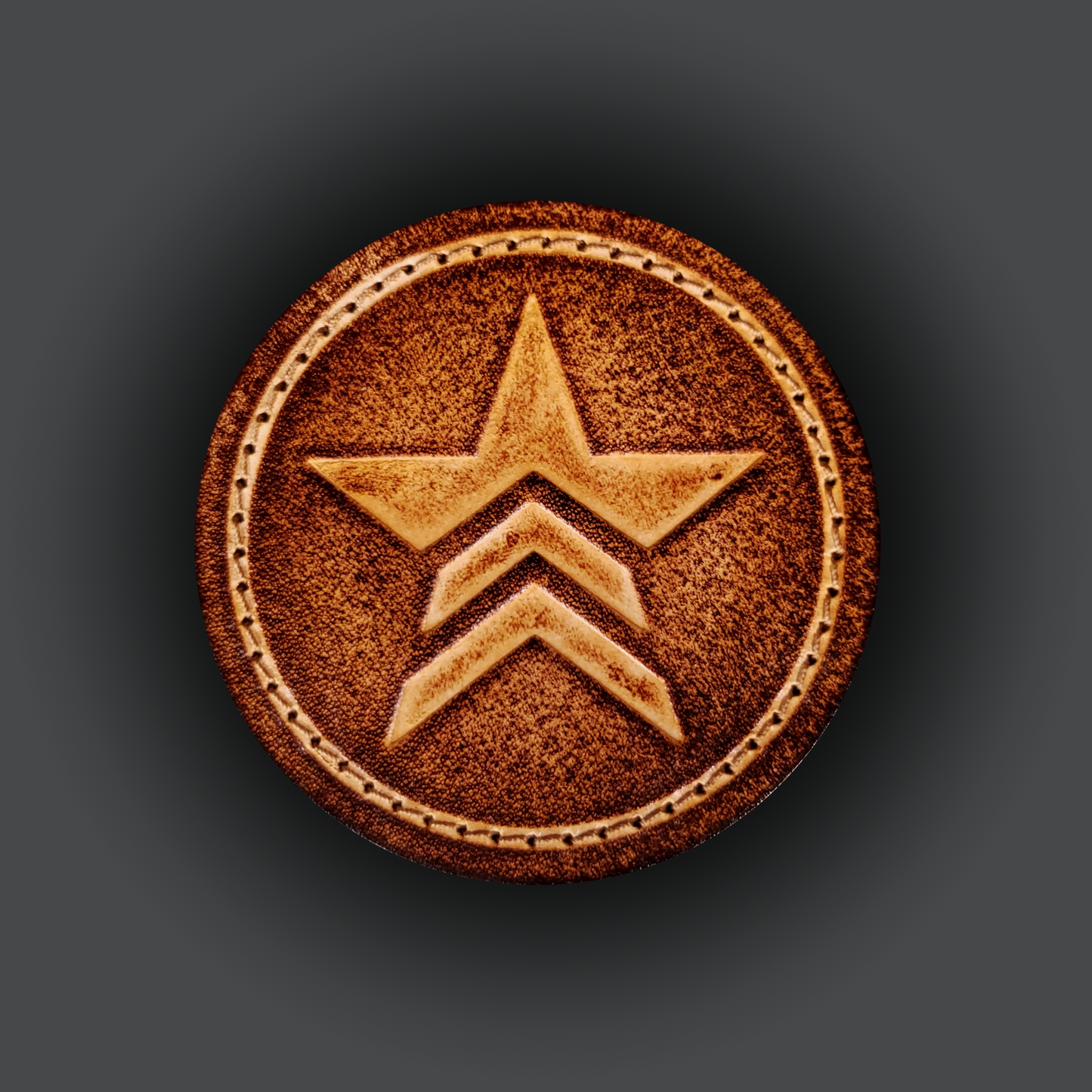 Brown leather velcro patch embossed with a star symbol with chevrons from the Mass Effect franchise.
