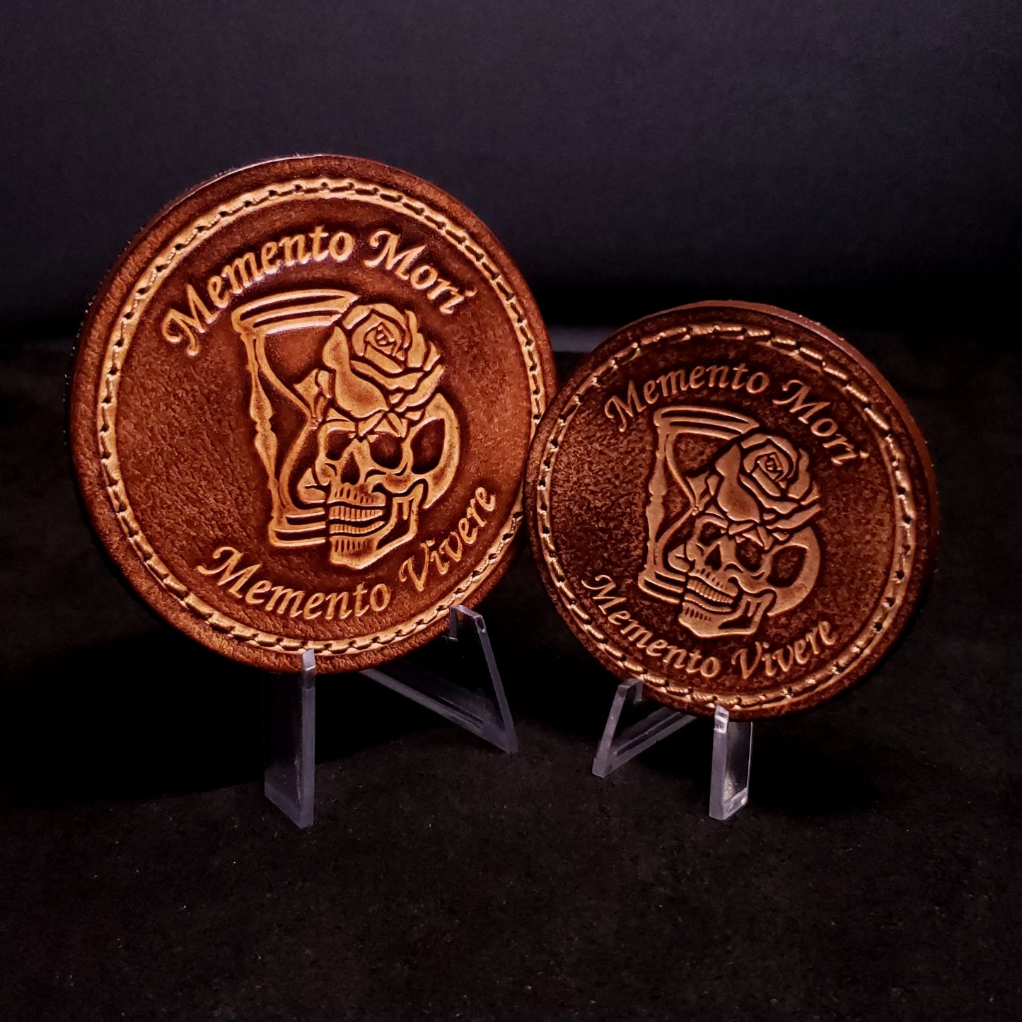 Two brown leather velcro patches with text that and an image of a skull, rose, and hourglass, posed on a black background.