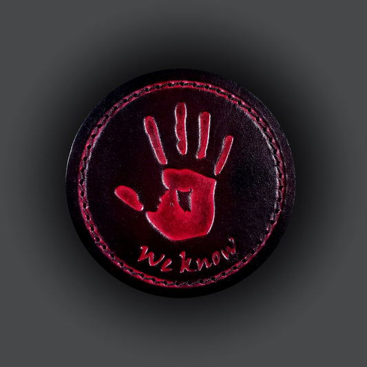 Black leather velcro patch featuring text that says "We know", and a red image of a hand print from the Elder Scrolls franchise.