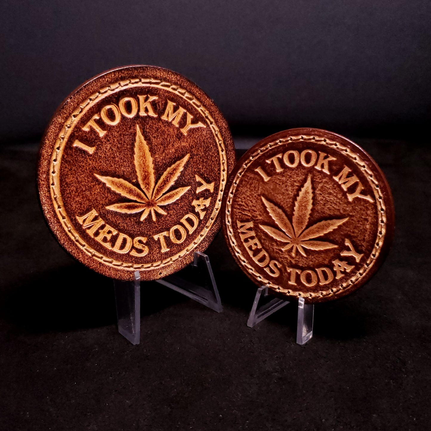 Two brown leather velcro patches embossed with a five leaf plant and text that says "I took my meds today", posed on a black background.