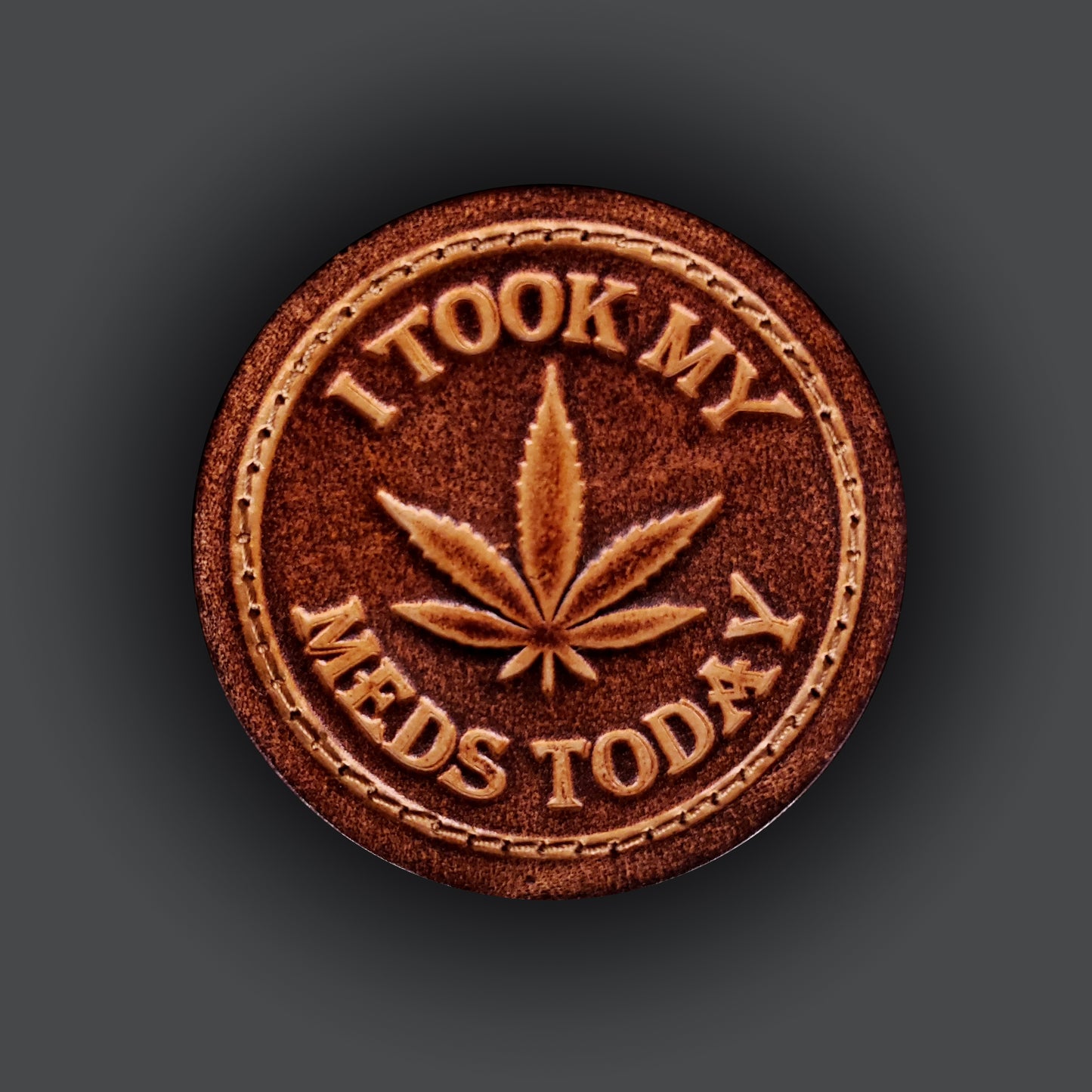 Brown leather velcro patch embossed with a five leaf plant and text that says "I took my meds today".