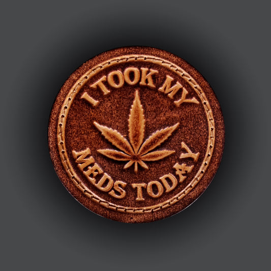 Brown leather velcro patch embossed with a five leaf plant and text that says "I took my meds today".