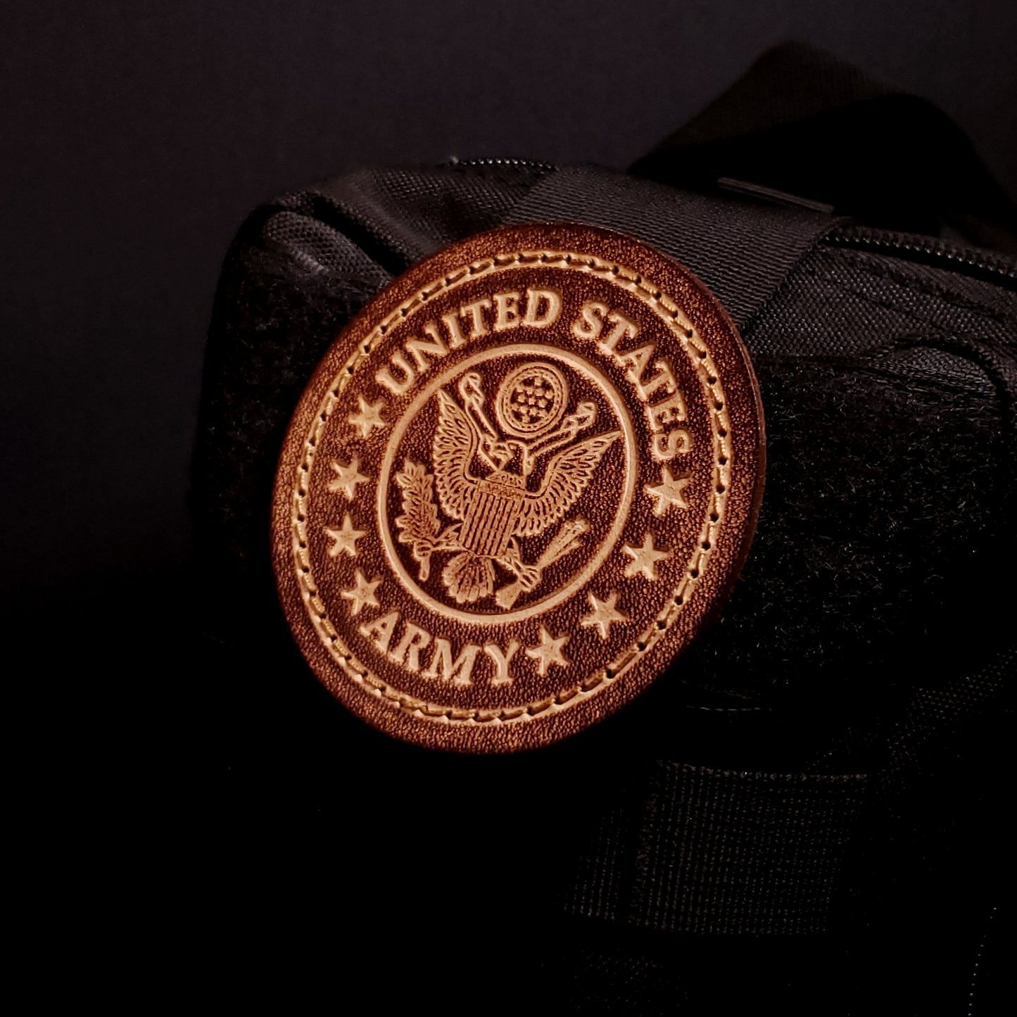 Brown leather velcro patch embossed with text and the united states army emblem, affixed to a bag.