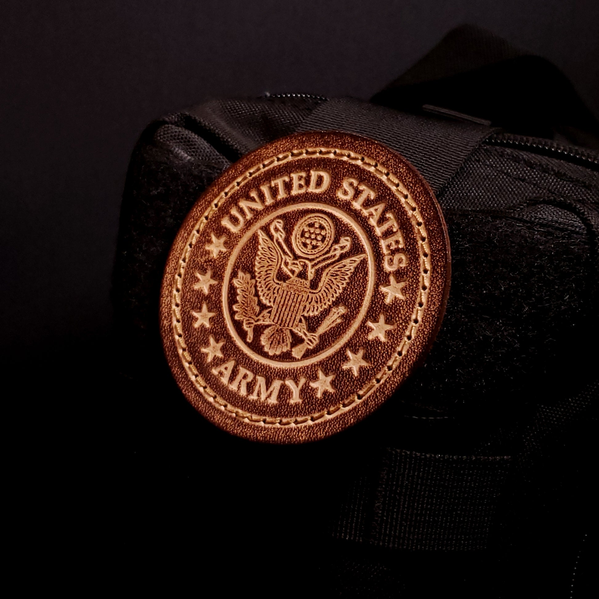 Brown leather velcro patch embossed with text and the united states army emblem, affixed to a bag.