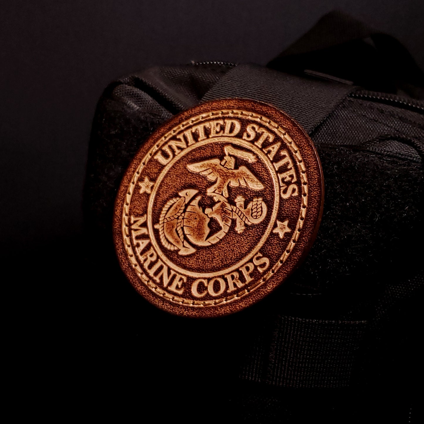 Brown leather velcro patch embossed with text and the United States Marine Corps emblem, affixed to a bag.