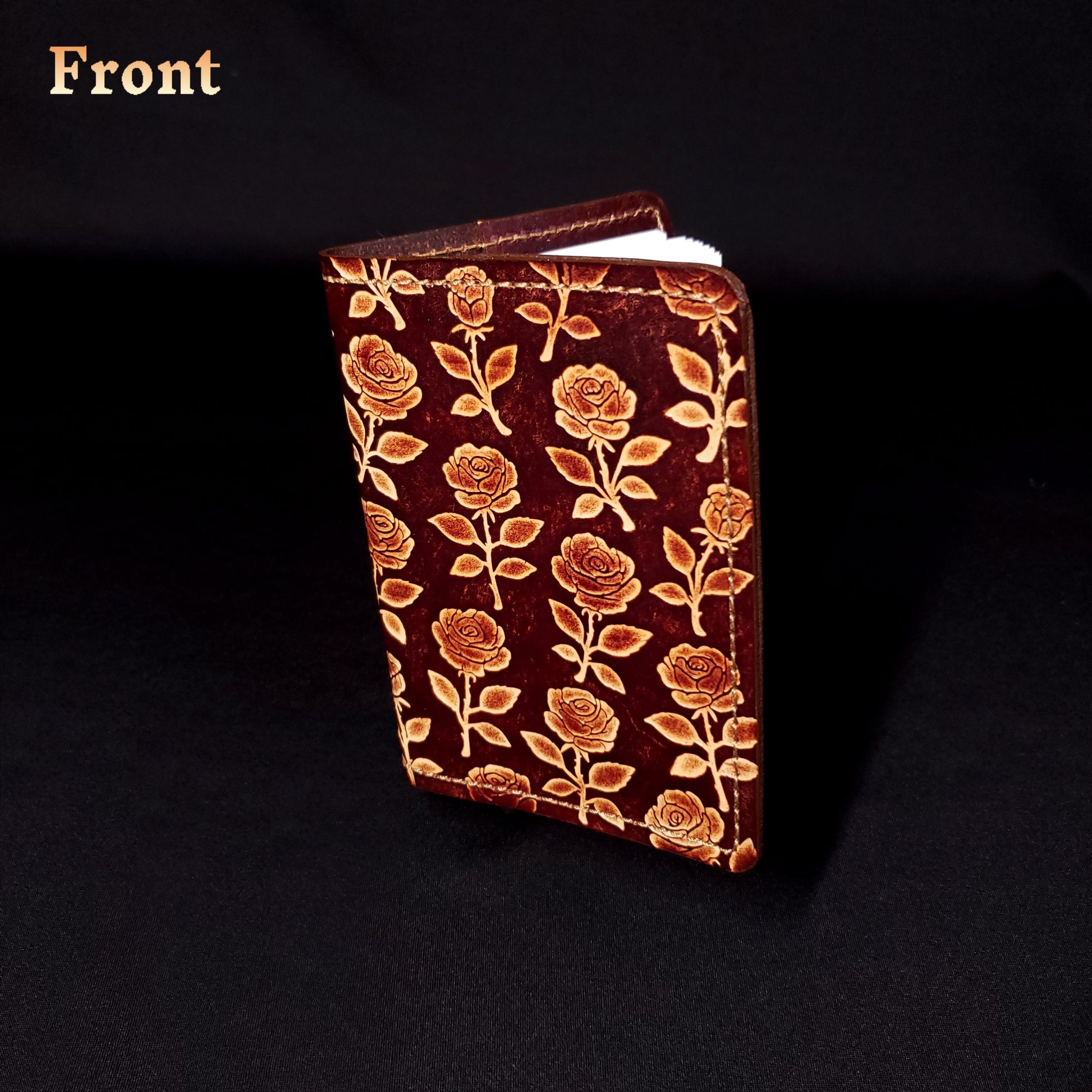 Brown leather mini-composition cover that's embossed with a floral rose pattern, closed and viewed from the front.
