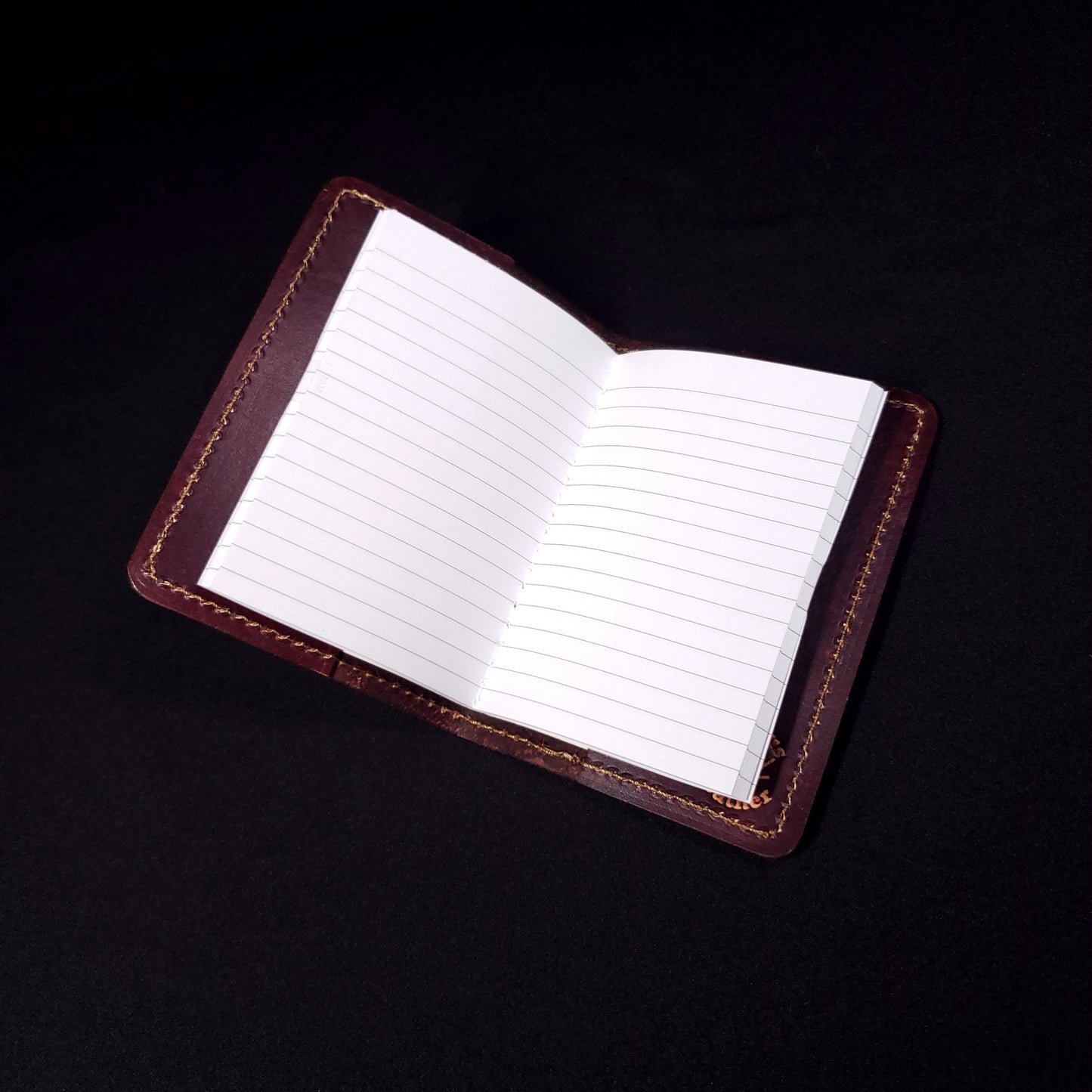 Brown leather mini-composition cover that's embossed with a floral rose pattern, opened with lined pages.