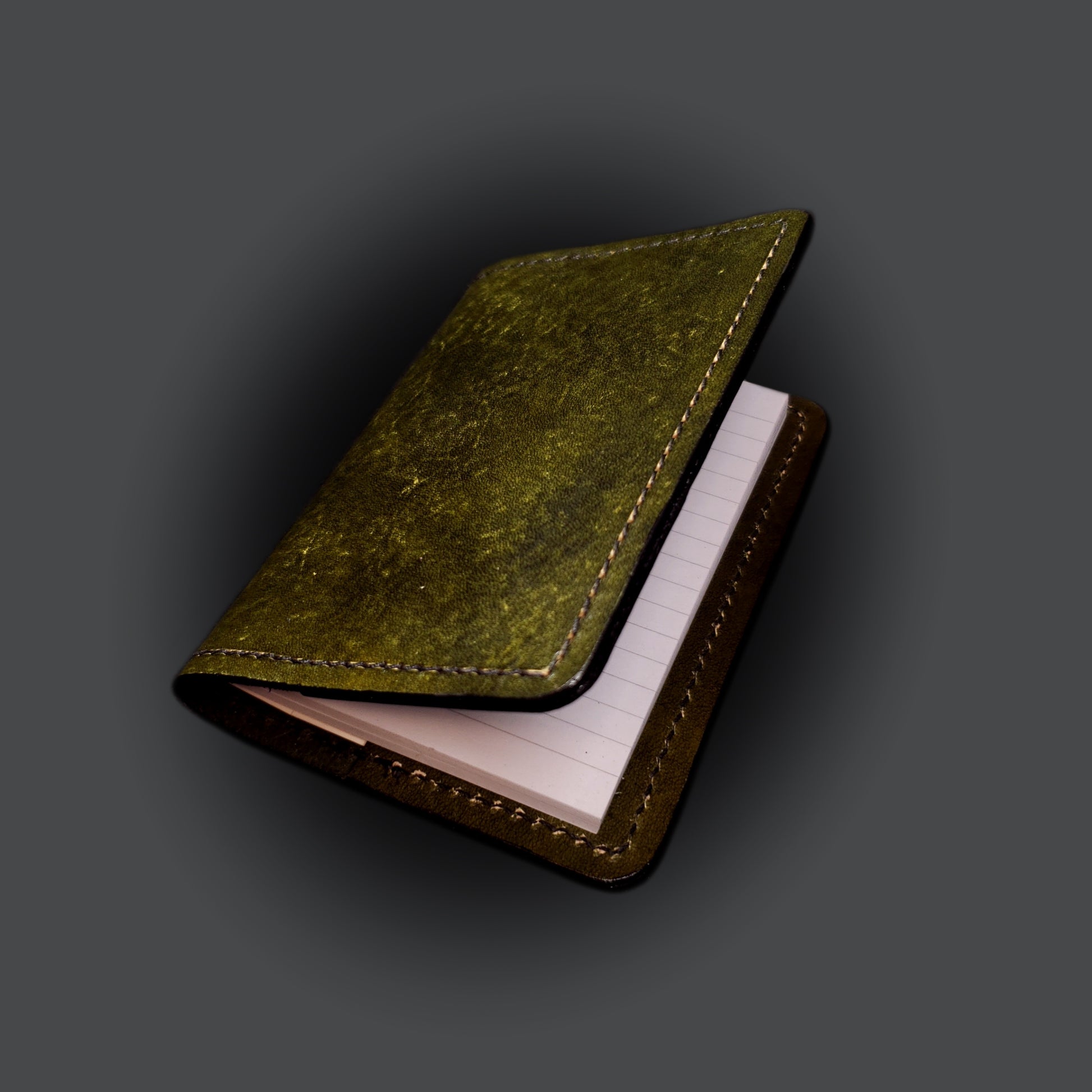 Olive-green leather mini-composition cover on a grey background
