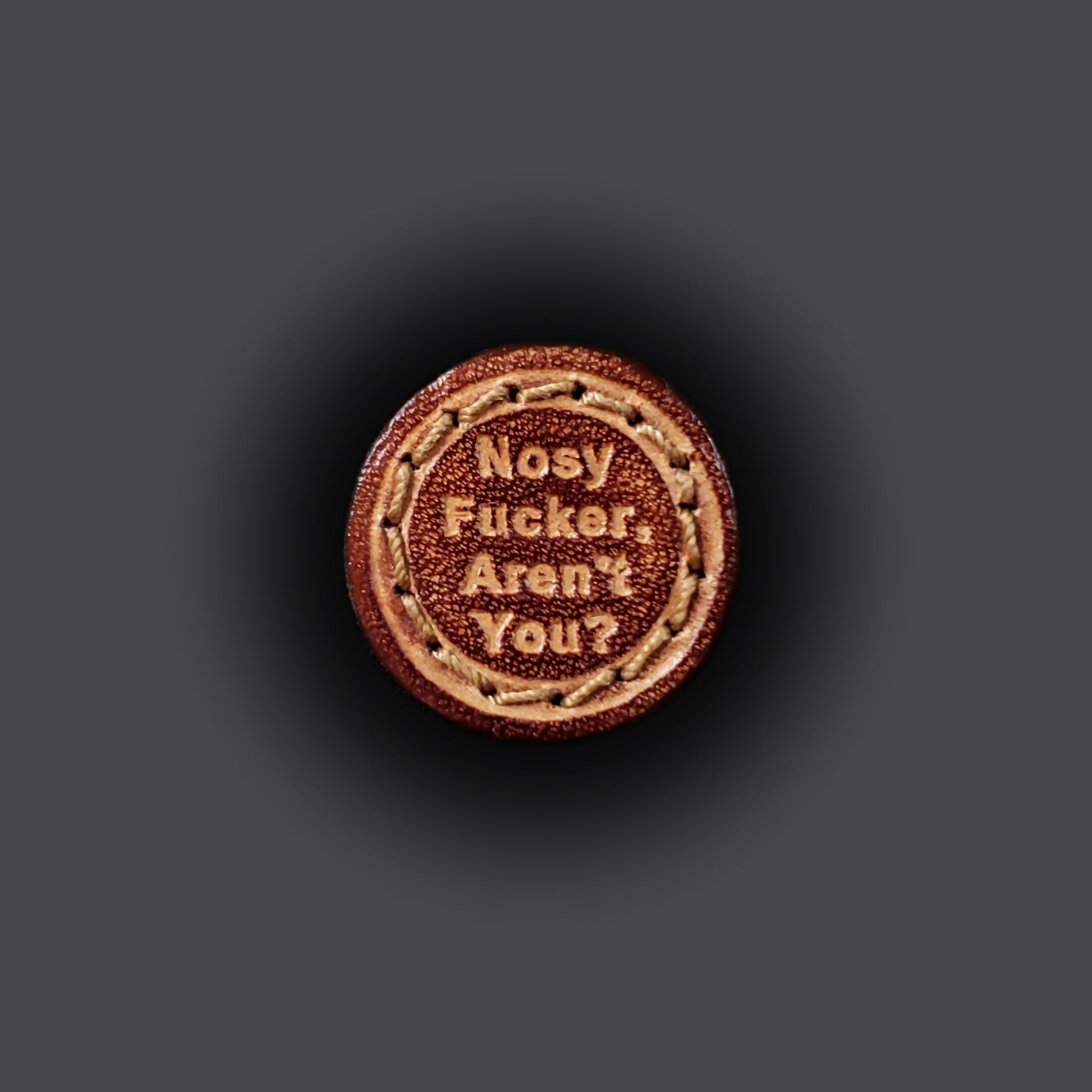 Small leather velcro patch embossed with text that says "Nosy fucker, aren't you?"