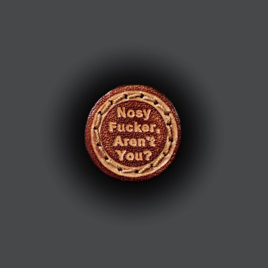 Small leather velcro patch embossed with text that says "Nosy fucker, aren't you?"