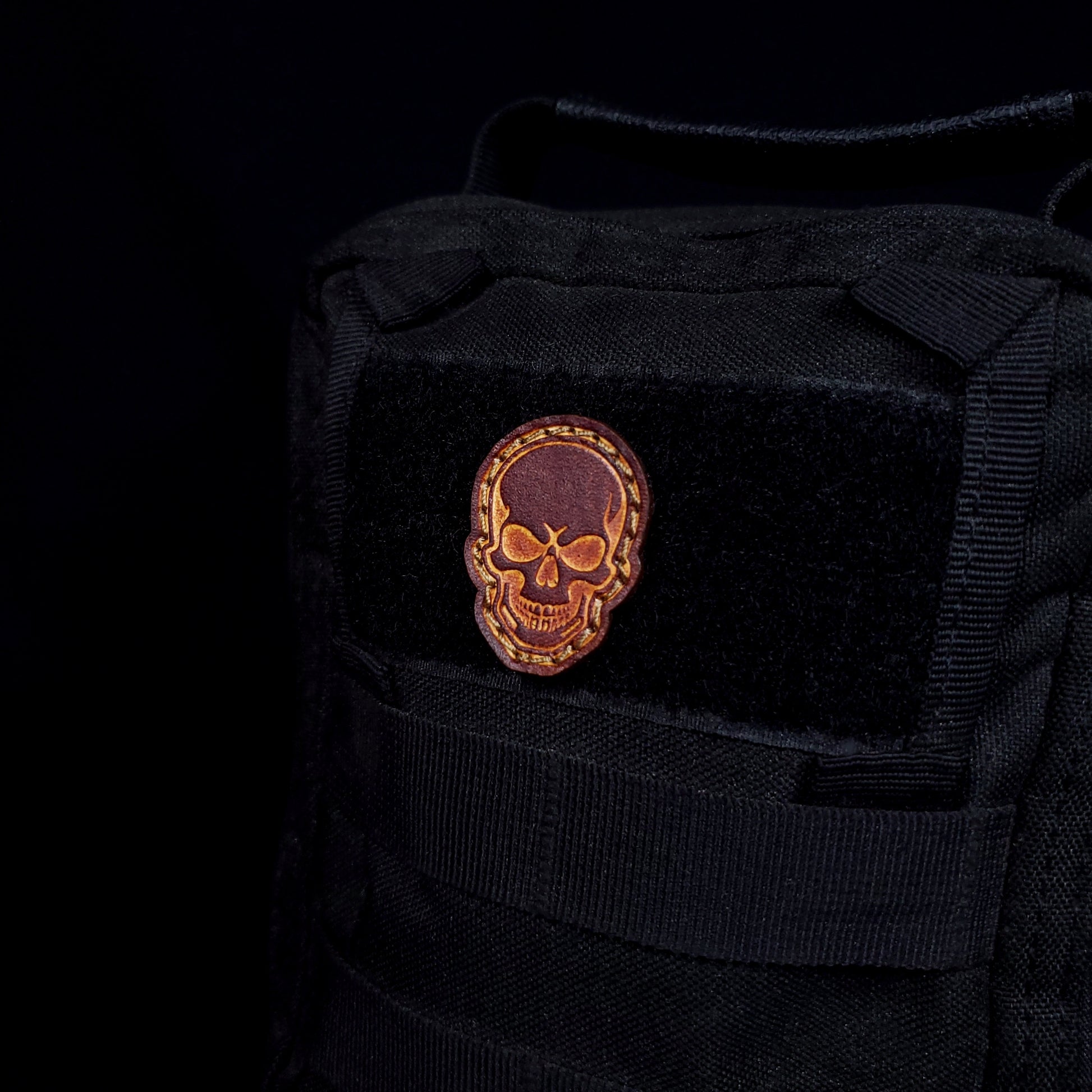 Small leather velcro patch embossed with a skull, affixed to a bag.